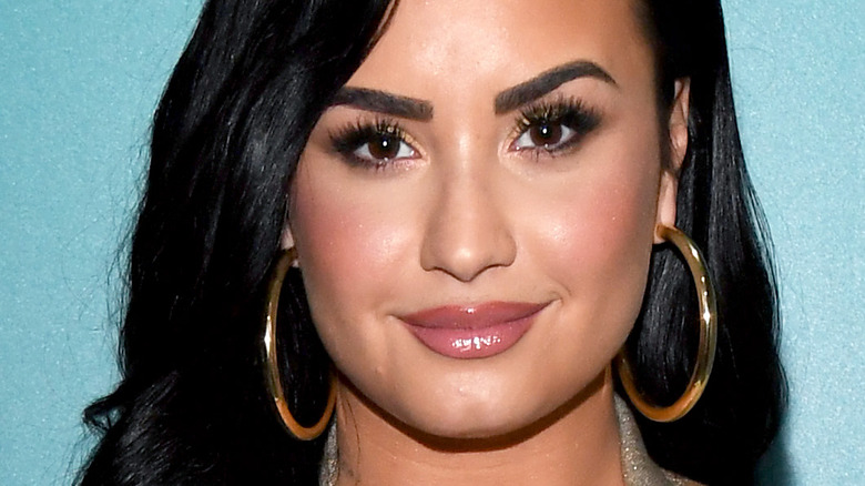 Demi Lovato with slight smile and hoop earrings