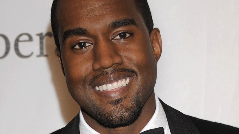 Kanye West smiles, wearing a tuxedo 