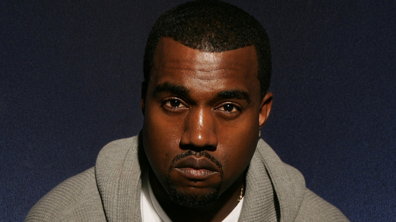 Kanye West wearing a gray hoodie, stares at camera