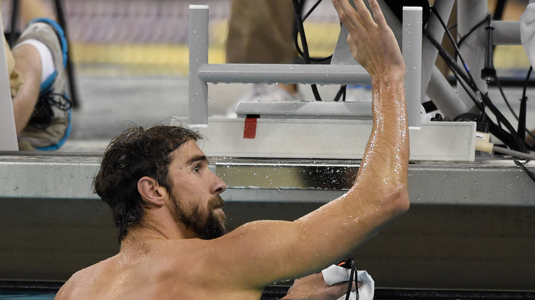 Michael Phelps waving to a fan in the pool