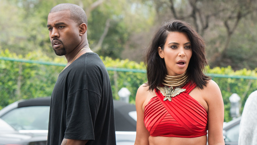 Kanye West and Kim Kardashian backs to one another standing outside