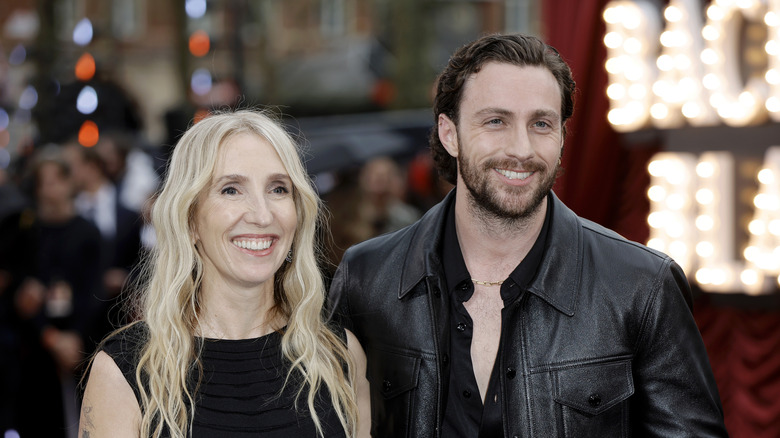 Sam and Aaron Taylor-Johnson smiling while posing together in matching all-black outfits