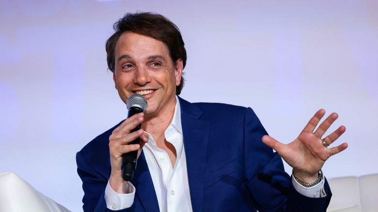 Ralph Macchio in a blue suit speaking at an event