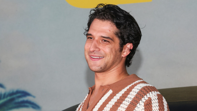 Tyler Posey wear a brown and white striped sweater.