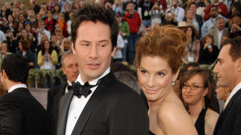Sandra Bullock smiling behind Keanu Reeves
