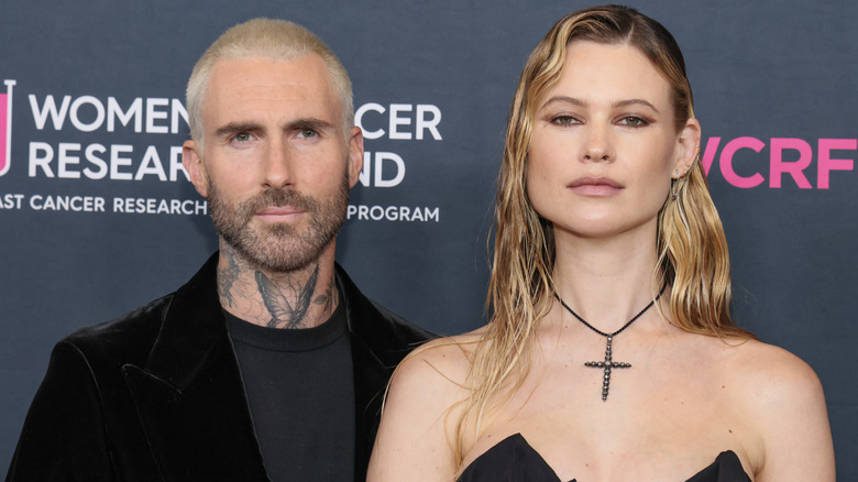 Adam Levine and Behati Prinsloo frowning on the red carpet.