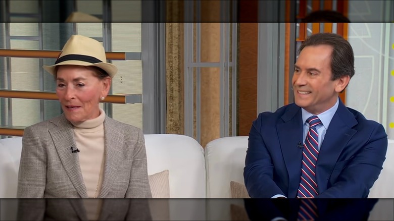 Judge Judy and Adam Levy sitting on a couch.