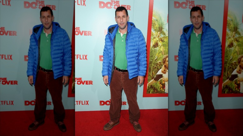 Adam Sandler posing on the red carpet in a blue jacket and green shirt