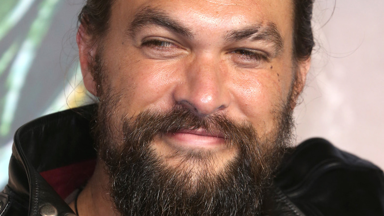 Jason Momoa grins in a leather jacket