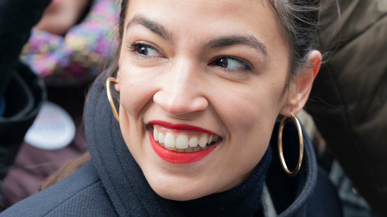 Alexandria Ocasio-Cortez smiling with red lipstick