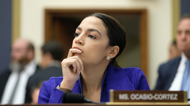 Alexandria Ocasio-Cortez listening while leaning her chin on her hand