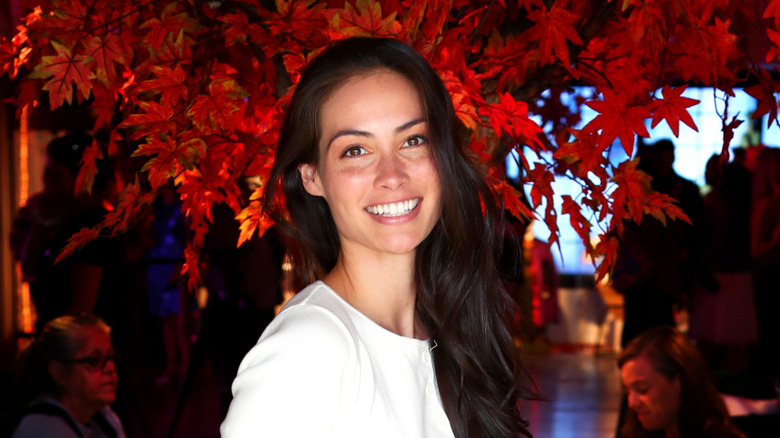 Caitlin McHugh smiling in front of illuminated red tree leaves