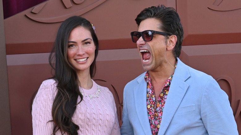 Caitlin McHugh smiling next to John Stamos miming a scream