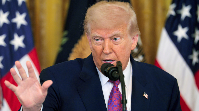 Donald Trump speaking to the press with hand outstretched