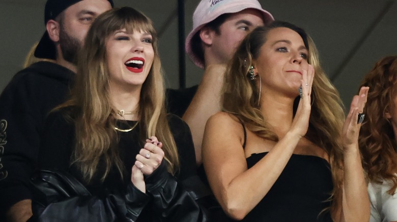 Blake Lively and Taylor Swift cheer at a game, while surrounded by other sports fans.