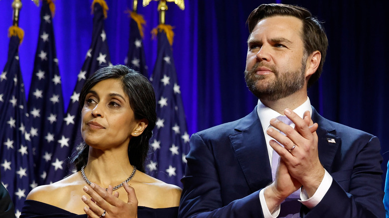 Usha and JD Vance clap while standing side by side.
