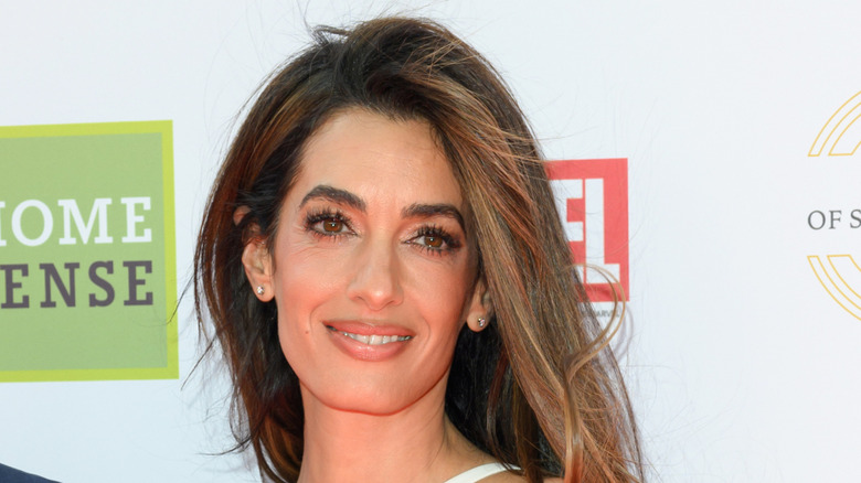 Amal Clooney smiling in front of backdrop