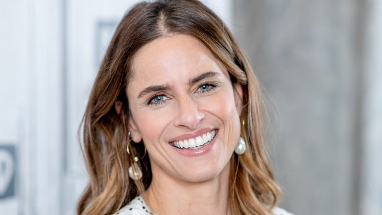 Amanda Peet smiles in pearl earrings