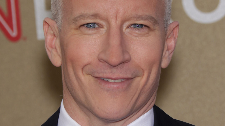 Anderson Cooper smiles in a suit and tie
