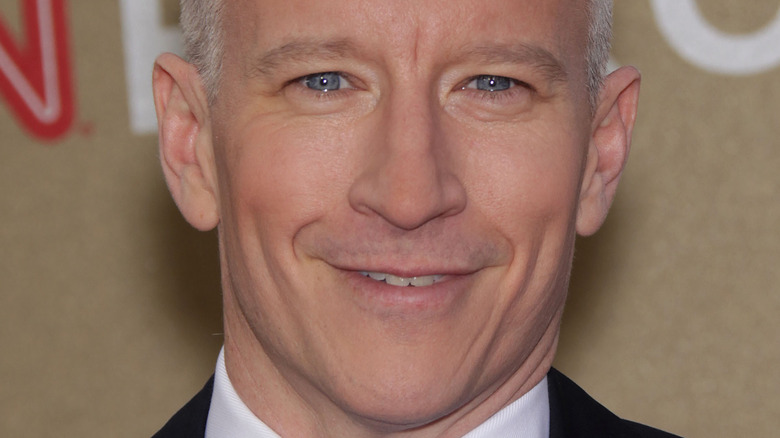Anderson Cooper smiles in a suit and tie
