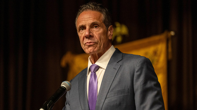 Andrew Cuomo making a speech while wearing a purple tie and gray suit