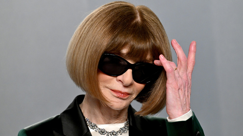Anna Wintour adjusts her hair on the red carpet