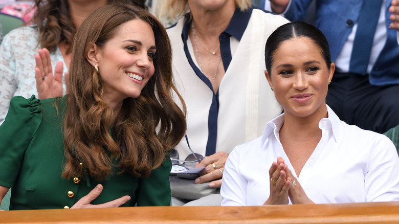 Kate Middleton and Meghan Markle smiling and clapping at Wimbledon