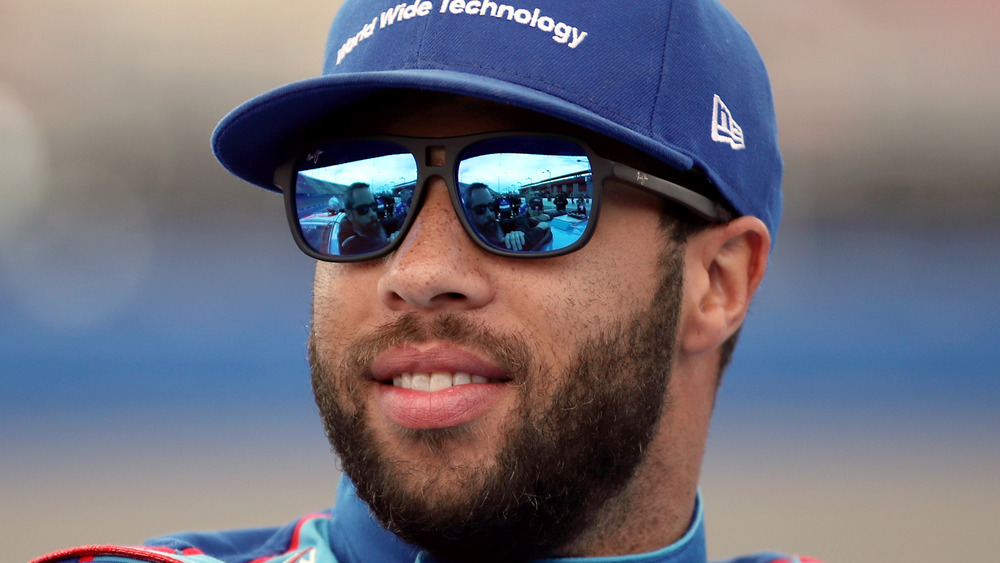 Bubba Wallace in blue reflective shades looks out at the crowd before a race