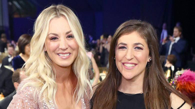 Kaley Cuoco and Mayim Bialik smiling in a room full of people.