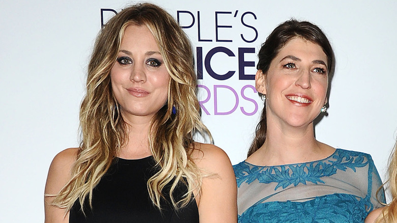 Kaley Cuoco wearing her hair in loose waves and Mayim Bialik with hers pulled back in a low ponytail.