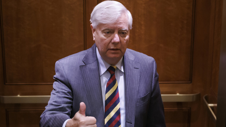 Lindsey Graham does a thumbs up while speaking to reporters.