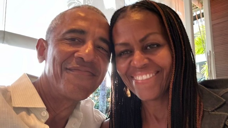 Barack and Michelle Obama posing for a smiling selfie with heads pressed together
