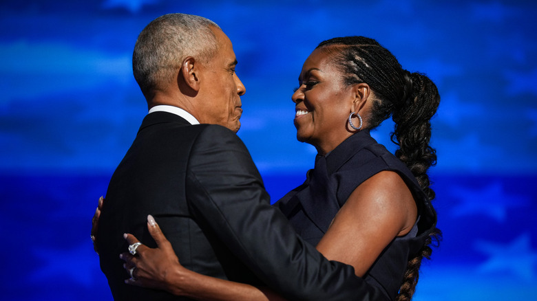 Barack and Michelle Obama embrace on stage