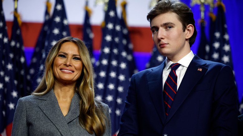 Barron Trump standing next to his smiling mother, Melania Trump, in a suit
