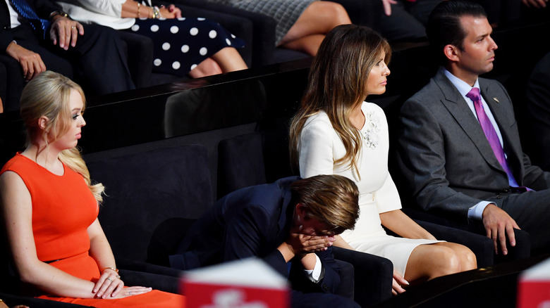 Barron Trump seated with face in hands