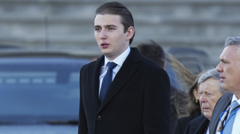 Sporting a jet black cashmere coat, Barron Trump looks ahead while taking a walk.