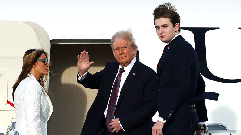Melania, Donald, and Barron Trump boarding a plane, with Donald waving to the camera