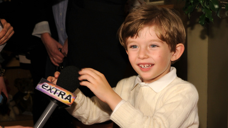 Young Barron Trump smiling and holding onto a microphone