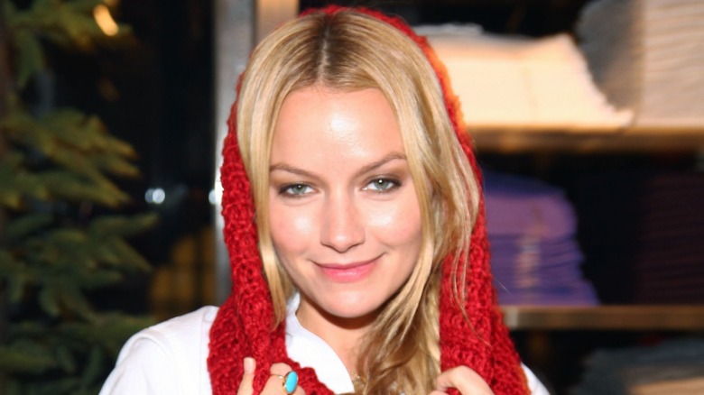 Wearing a knitted scarf over her head, Becki Newton displays a warm smile.