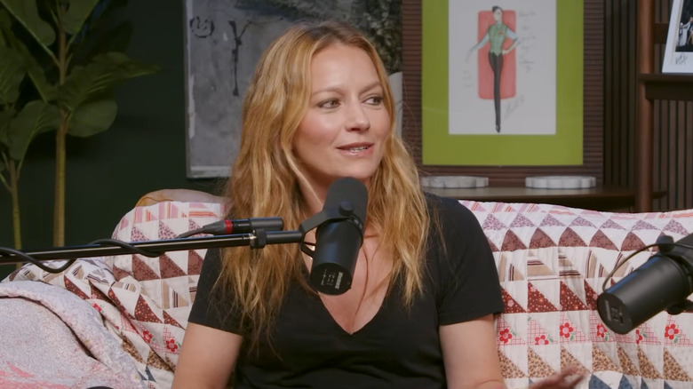 Becki Newton turns her head to the side while speaking into a microphone.