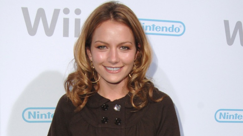Dressed in a dark outfit, Becki Newton wears a bright smile on the red carpet.