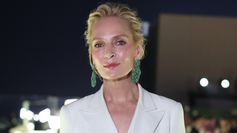 Uma Thurman wearing green statement earrings and a white blazer at the 