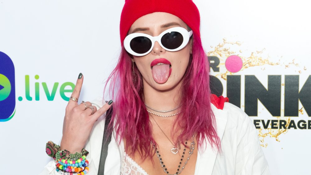 Bella Thorne in a red beanie and pink hair with white sunglasses