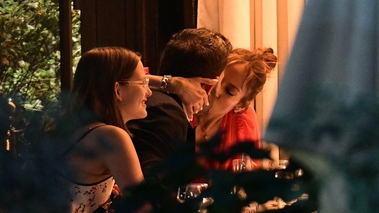 Violet Affleck smiling while JLo and Ben Affleck kiss