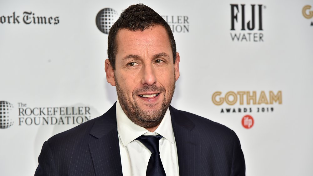 Adam Sandler looking off to the side, grinning