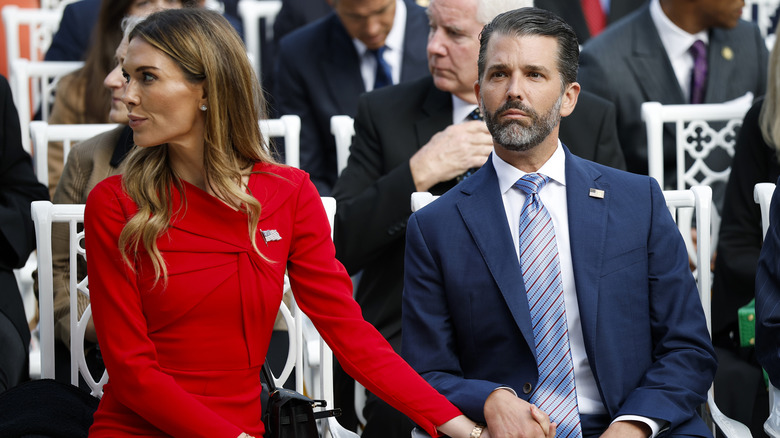 Bettina Anderson and Donald Trump Jr. holding hands while sitting.