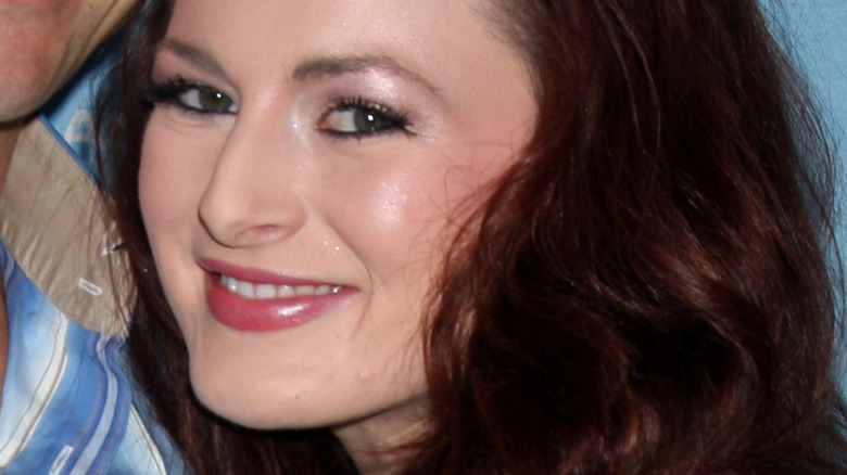 Rachel Reilly and Brendon Villegas (wearing glasses and a blue button down shirt) smile together at an event