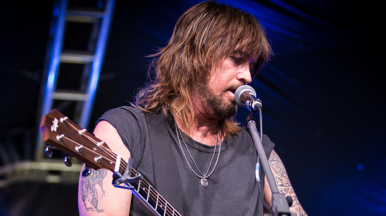Billy Ray Cyrus performing with guitar