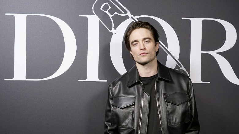 Robert Pattinson in front of DIOR logo
