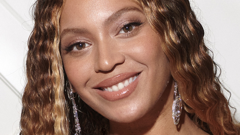 Beyonce smiling, with bronze eye makeup and dangling earrings